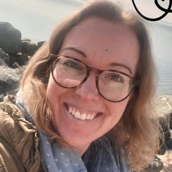 Maren lacht in die Kamera, hinter ihr Steine und die Ostsee