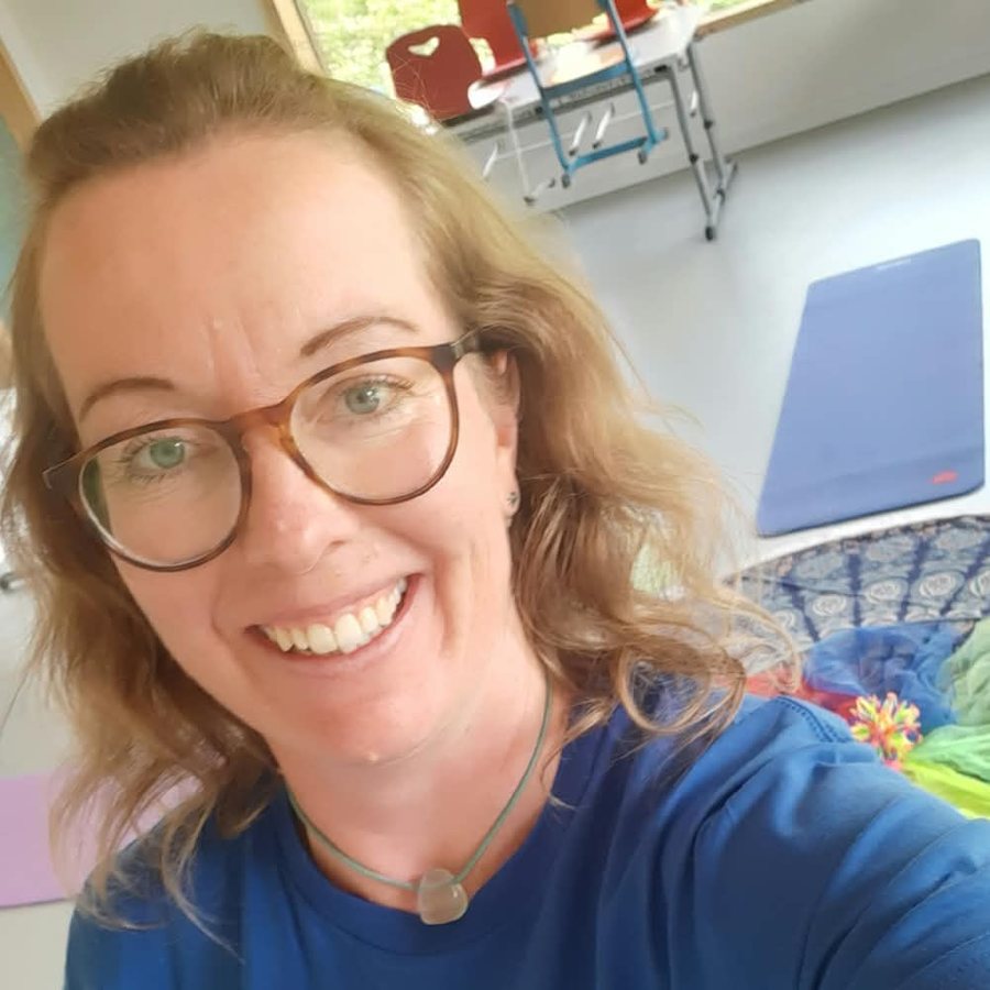 Maren lächelt in die Kamera, im Hintergrund Yogamatten und bunte Tücher